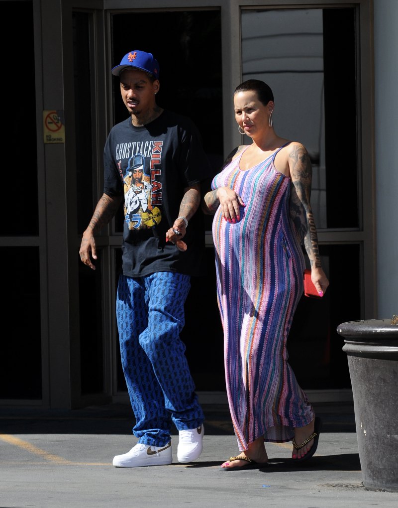 Pregnant Amber Rose cradles her baby bump while wearing a striped summer dress