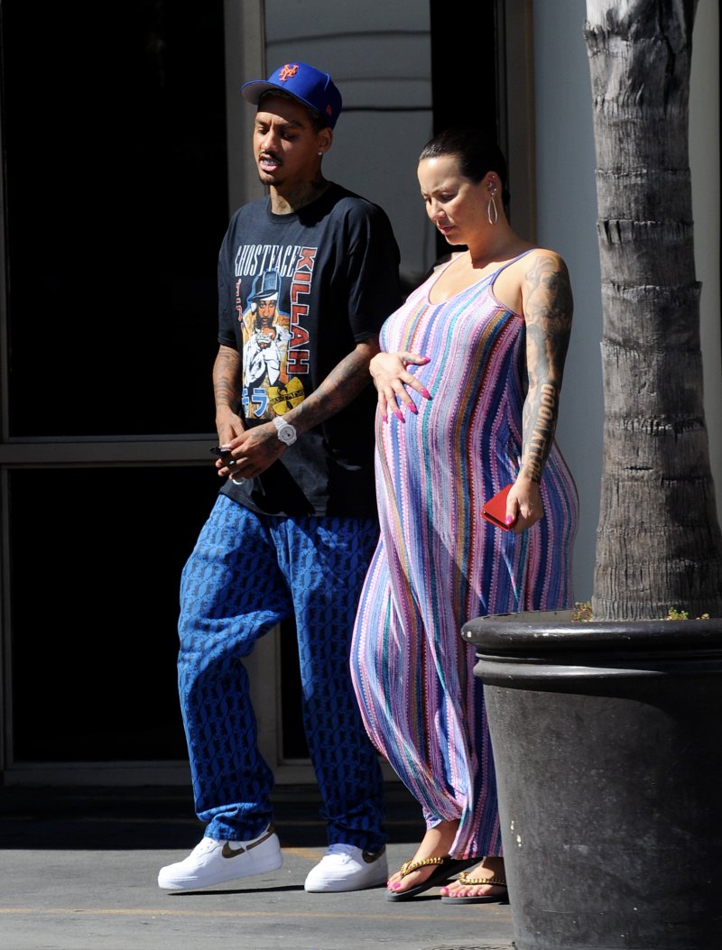 Pregnant Amber Rose cradles her baby bump while wearing a striped summer dress
