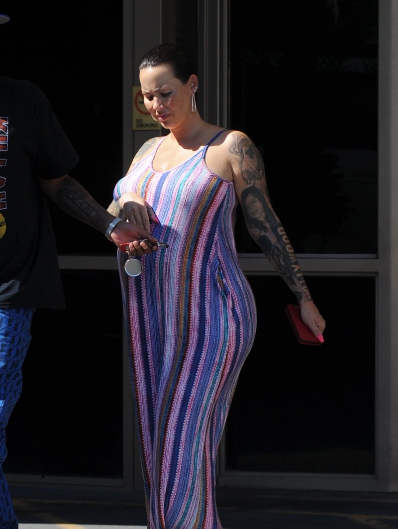 Pregnant Amber Rose cradles her baby bump while wearing a striped summer dress