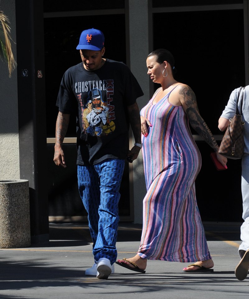 Pregnant Amber Rose cradles her baby bump while wearing a striped summer dress