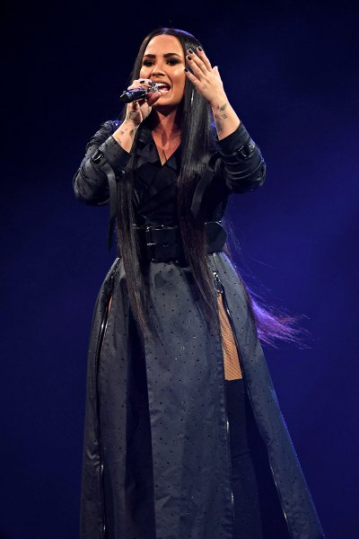 Demi Lovato Performs On Stage In Long Black Trench Coat With High Slits