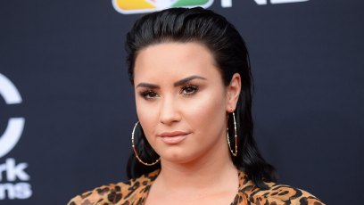 Demi Lovato Closeup In Leopard Print Dress With Hoop Earrings and Slicked Back Hair Smiling