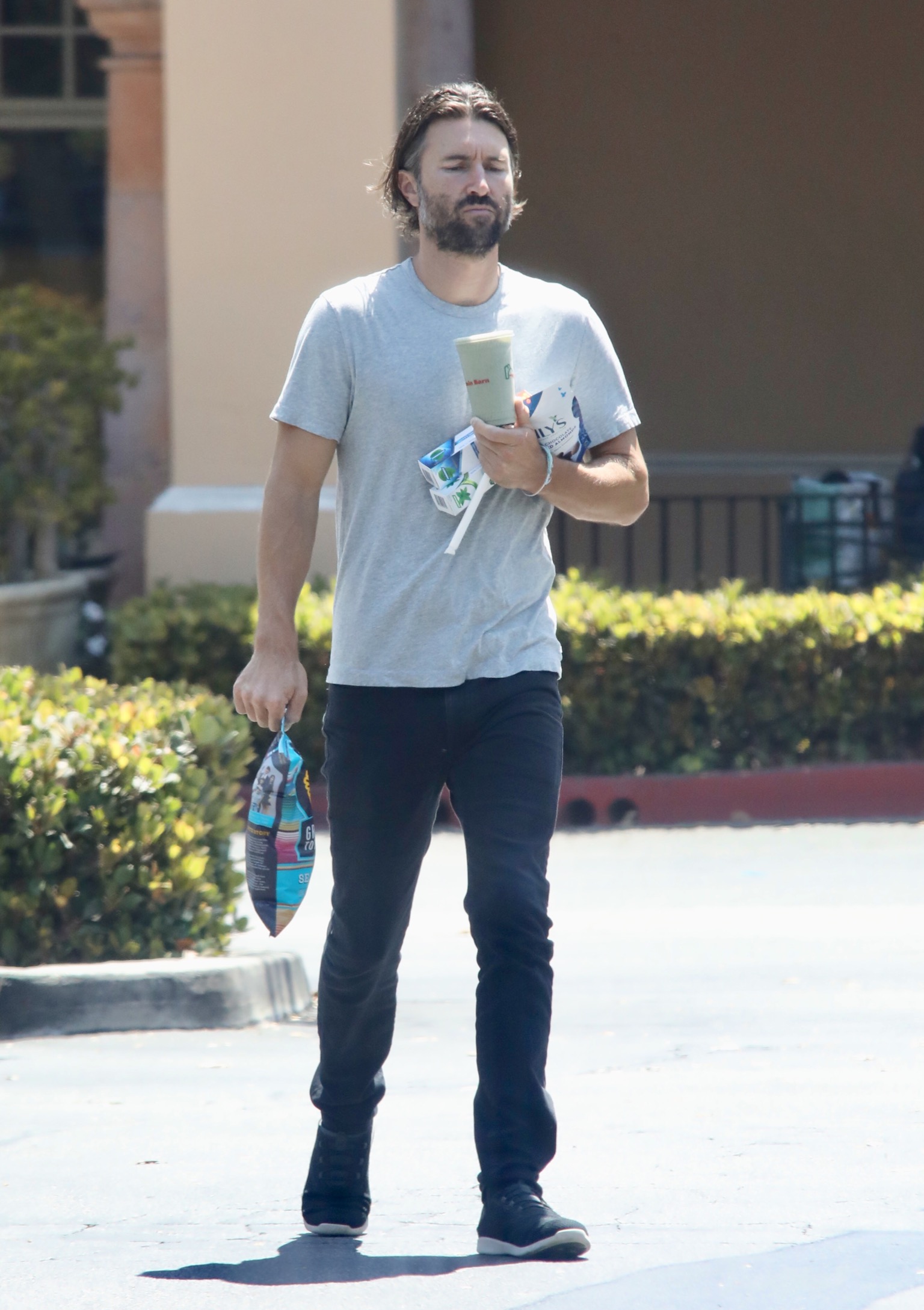 Brandon Jenner out running errands blue shirt and jeans holding snacks
