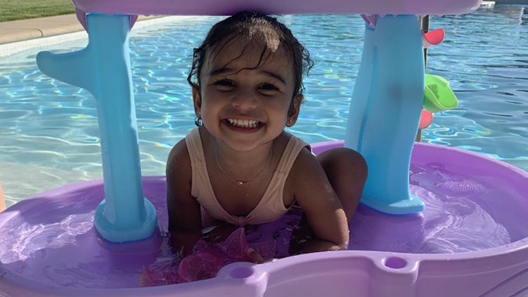 dream kardashian sits on purple pool toy and smiles