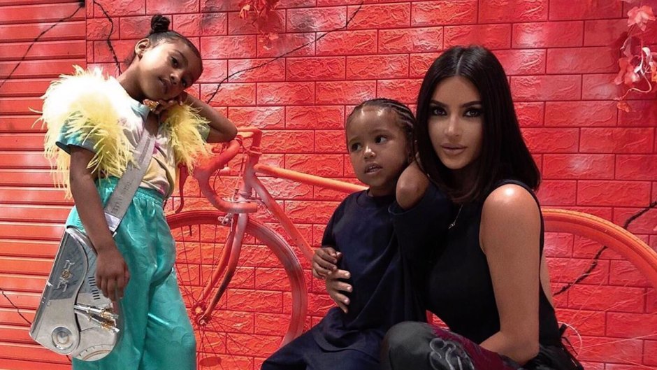 Kim Kardashian North West and Saint West in Japan Posing Against a Red Wall