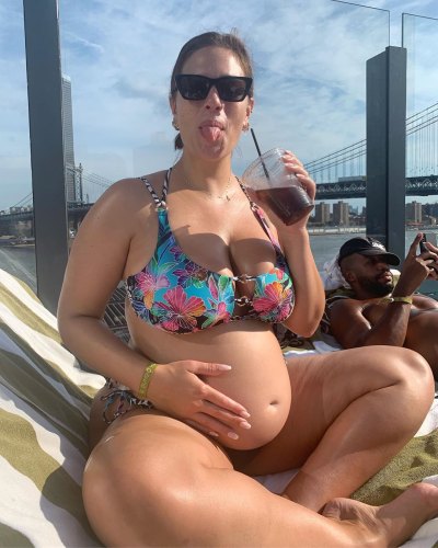 A pregnant Ashley Graham in a bikini posing with husband Justin Ervin