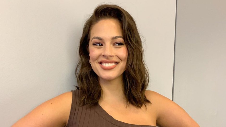 A pregnant Ashley Graham posing in a brown dress