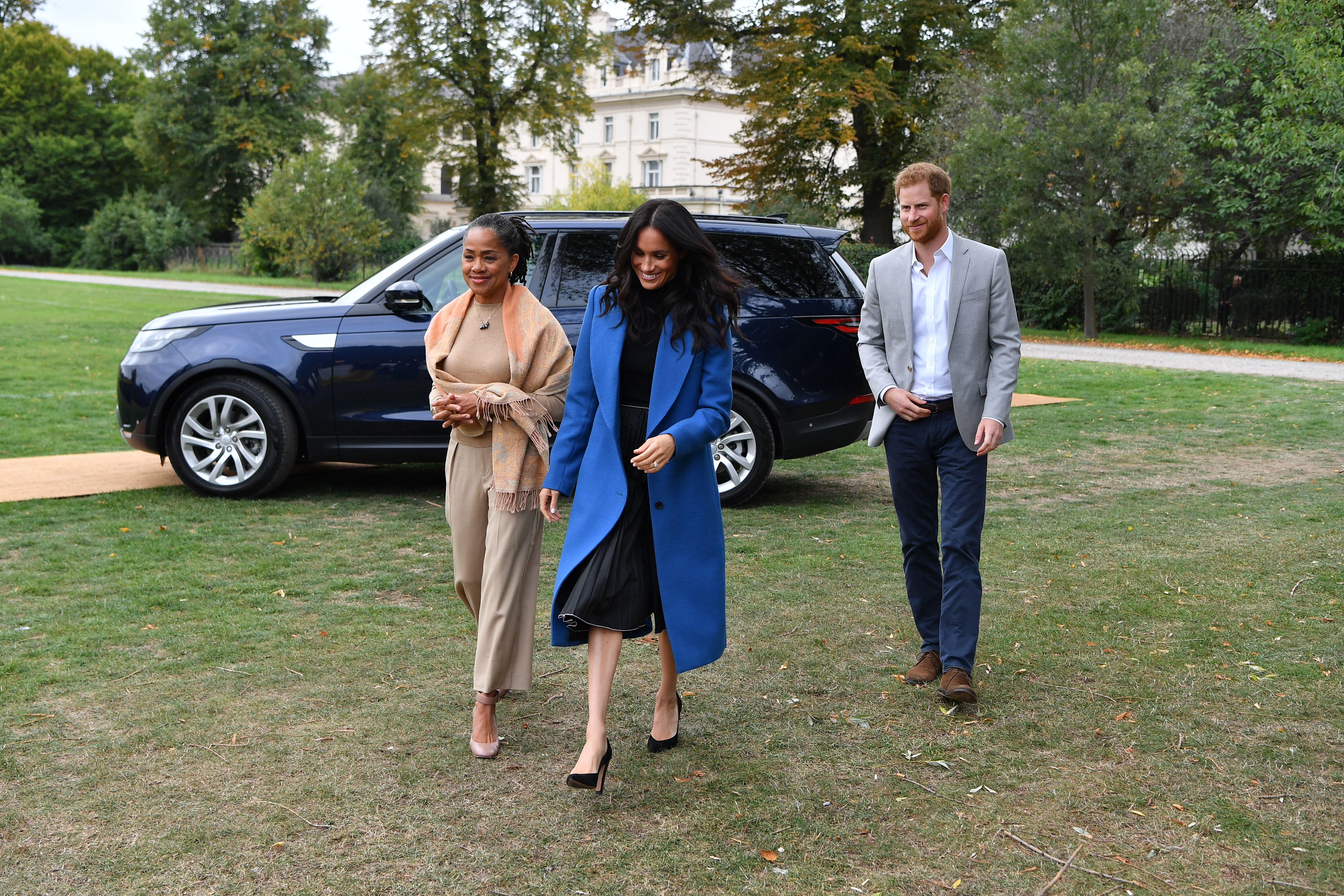 Doria Ragland, Meghan Markle and Prince Harry walking across the grass of Kensington Palace