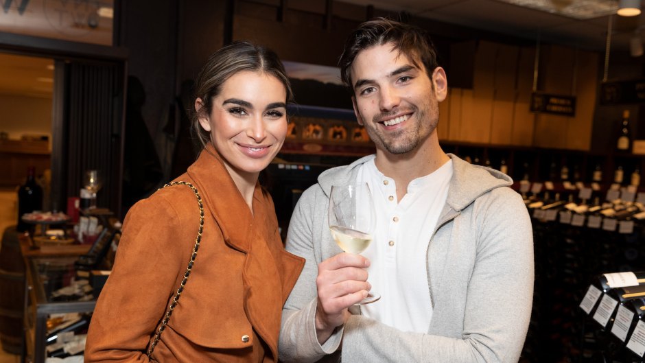 Ashley Iaconetti Wearing a Brown JAcket With Jared Haibon Wearing a Sweatshirt While Holding a Glass of Wine