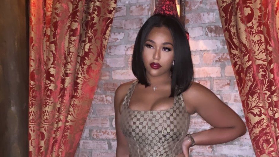 Jordyn Woods posing in a Gucci bustier, leather pants and nude heels