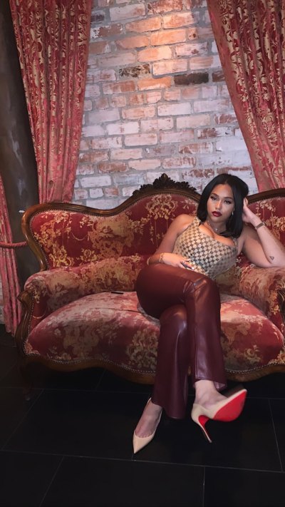 Jordyn Woods posing in a Gucci bustier, leather pants and nude heels