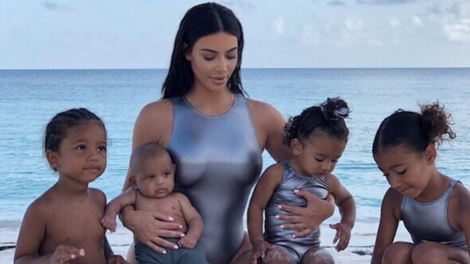Kim Kardashian and her four children on the beach wearing matching silver swimsuits
