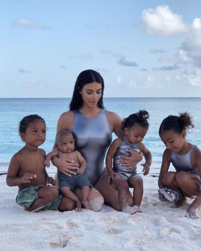 Kim Kardashian and her four children on the beach wearing matching silver swimsuits
