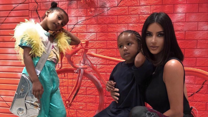 Kim Kardashian posing with Saint West and North West in front of a red wall in Japan
