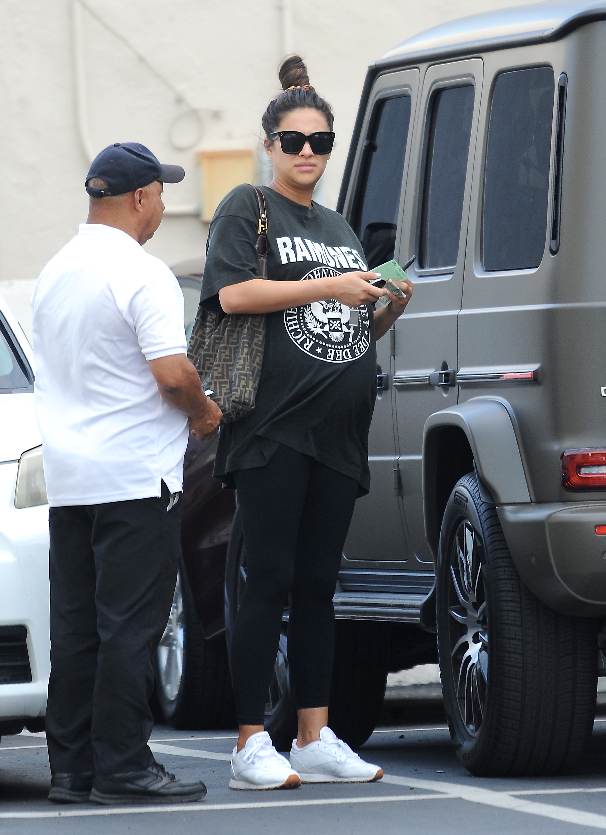 Pregnant Shay Mitchell wearing a Ramones T-Shirt, black leggings, sunglasses and white sneakers
