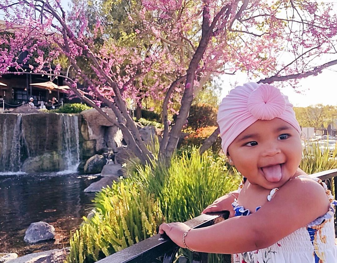 True Thompson sticking her tongue out wearing a pink turban