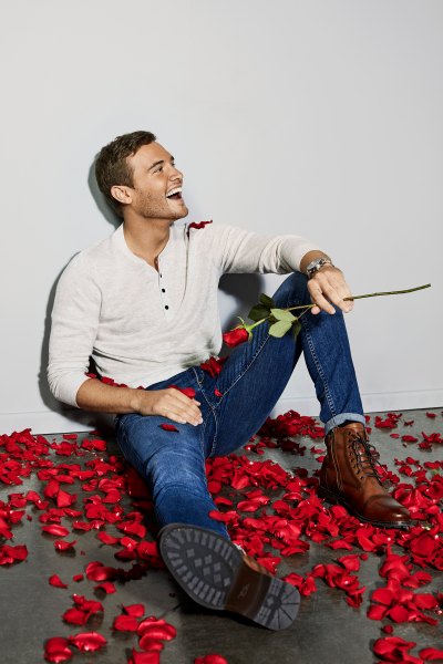 Bachelor Peter Weber Laughs While Holding a Rose in a Pile of Rose Petals