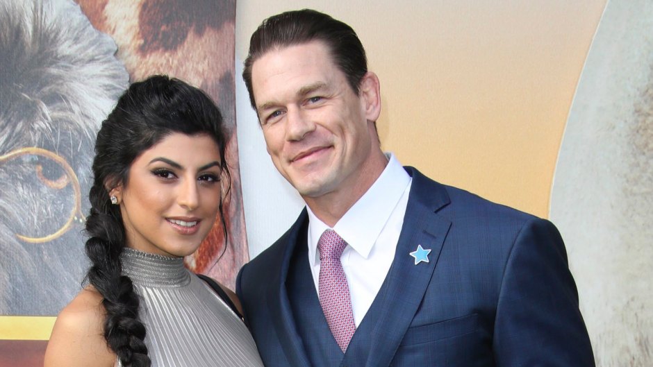 John Cena in Blue Suit and Pink Tie and Girlfriend Shay Shariatzadeh in Shimmery Silver Dress and Long Braid Smile on Red Carpet
