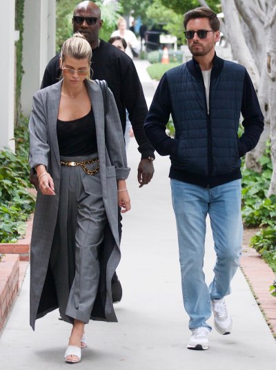 Sofia Richie Walks in Blue Dress Pants Black Tank Top and Long Blue Coat With Sunglasses While Walking WIth Boyfriend Scott Disick in Blue Jeans Blue Jacket and Sunglasses