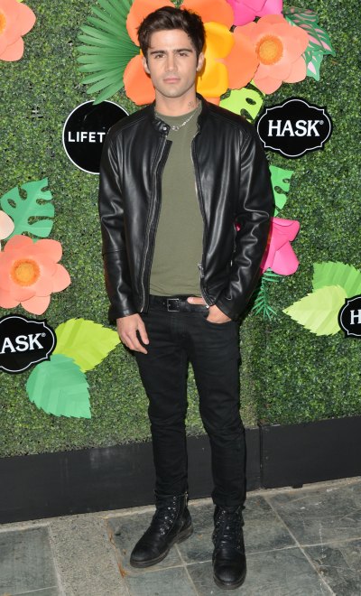 Max Ehrich Stands in Leather Coat and Tshirt