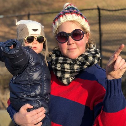 Amy Schumer Smiles Wearing Sunglasses a Hat and Scarf While Holding Son Gene in a Parka Hat and Sunglasses