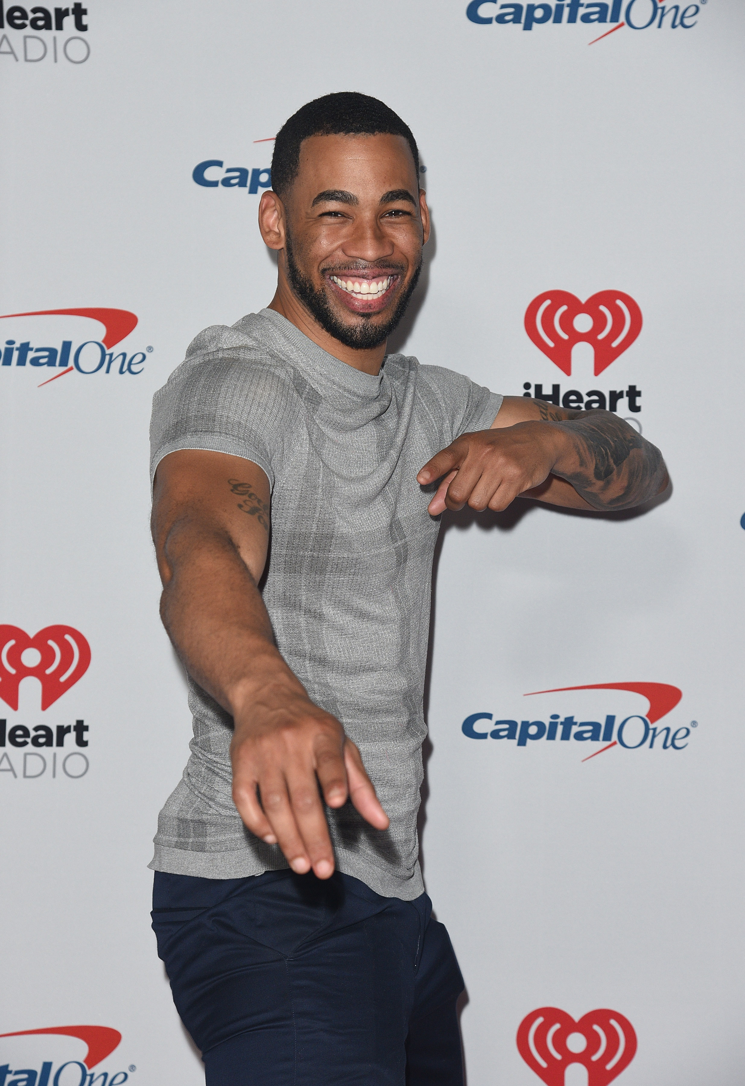 Bachelorette Contestant Mike Johnson Smiles and Points in Grey Tshirt