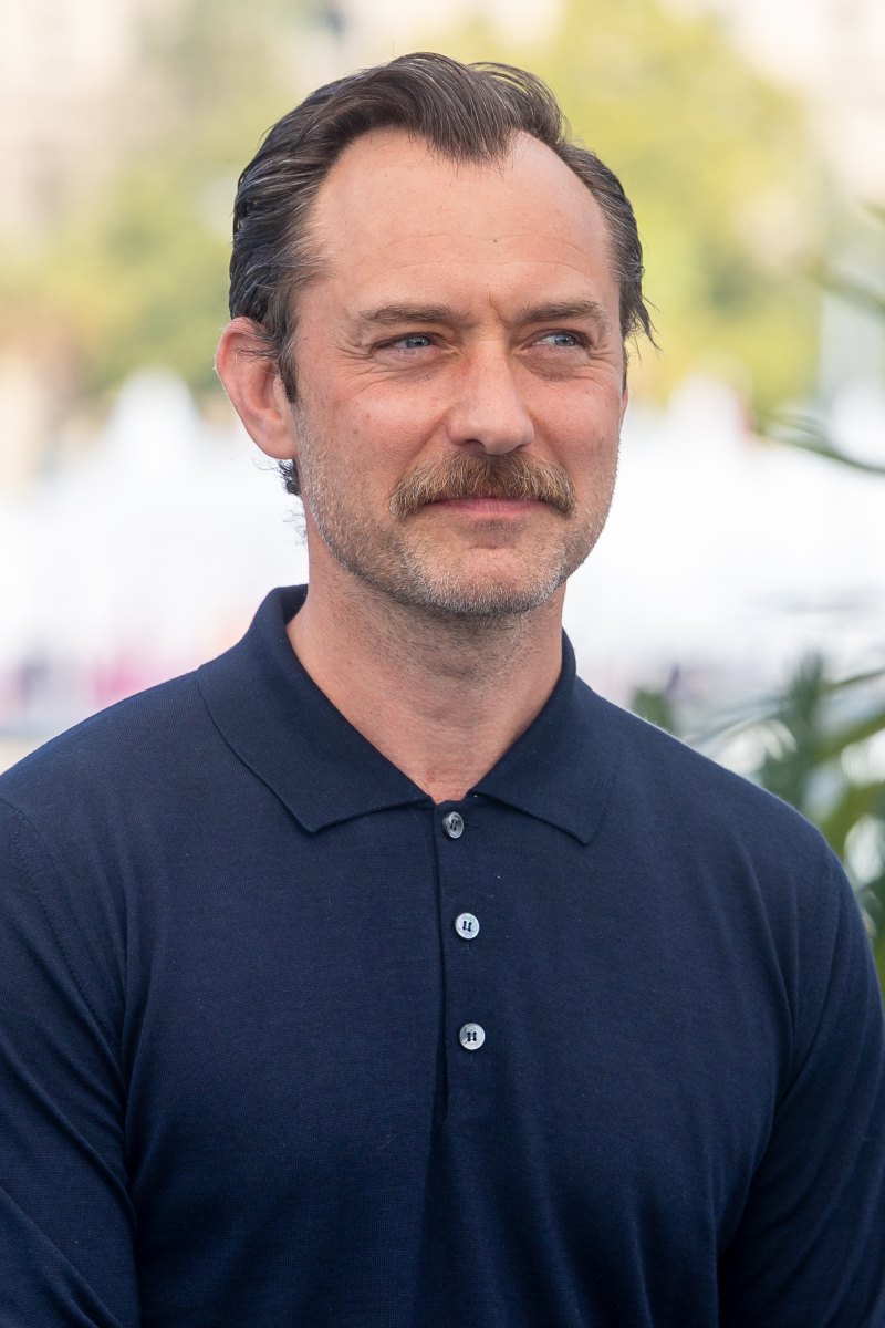 Jude Law wearing a navy blue polo shirt.