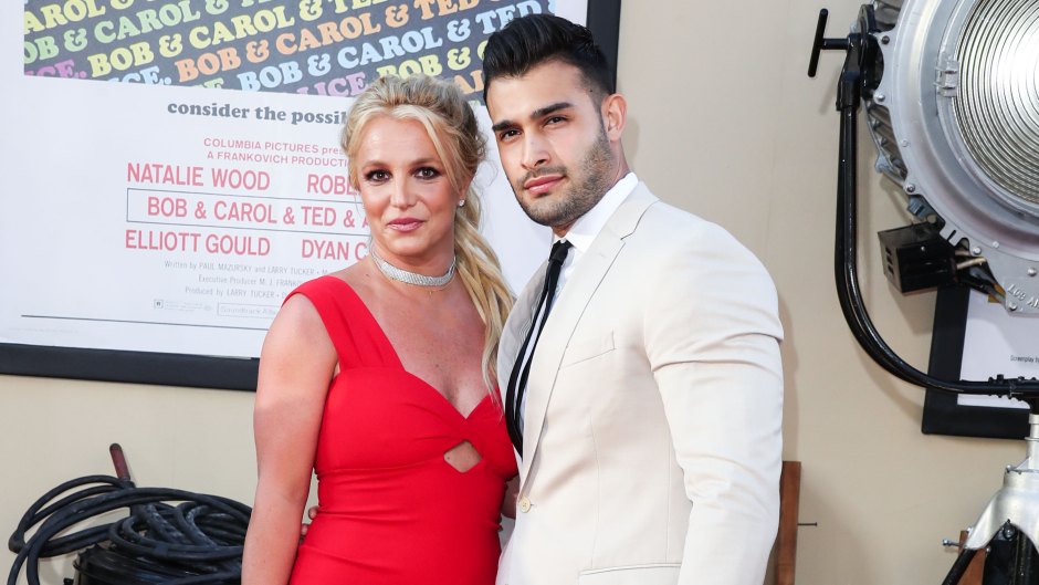 Britney Spears wearing a red dress standing next to her husband, Sam Asghari