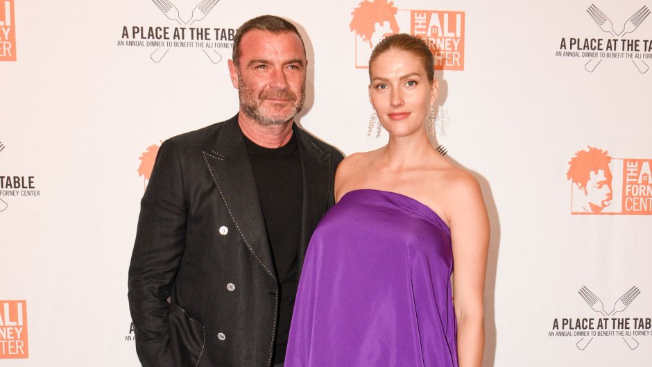Liev Schreiber wearing an all-black suit and wife Taylor Neisen wearing a purple strapless dress