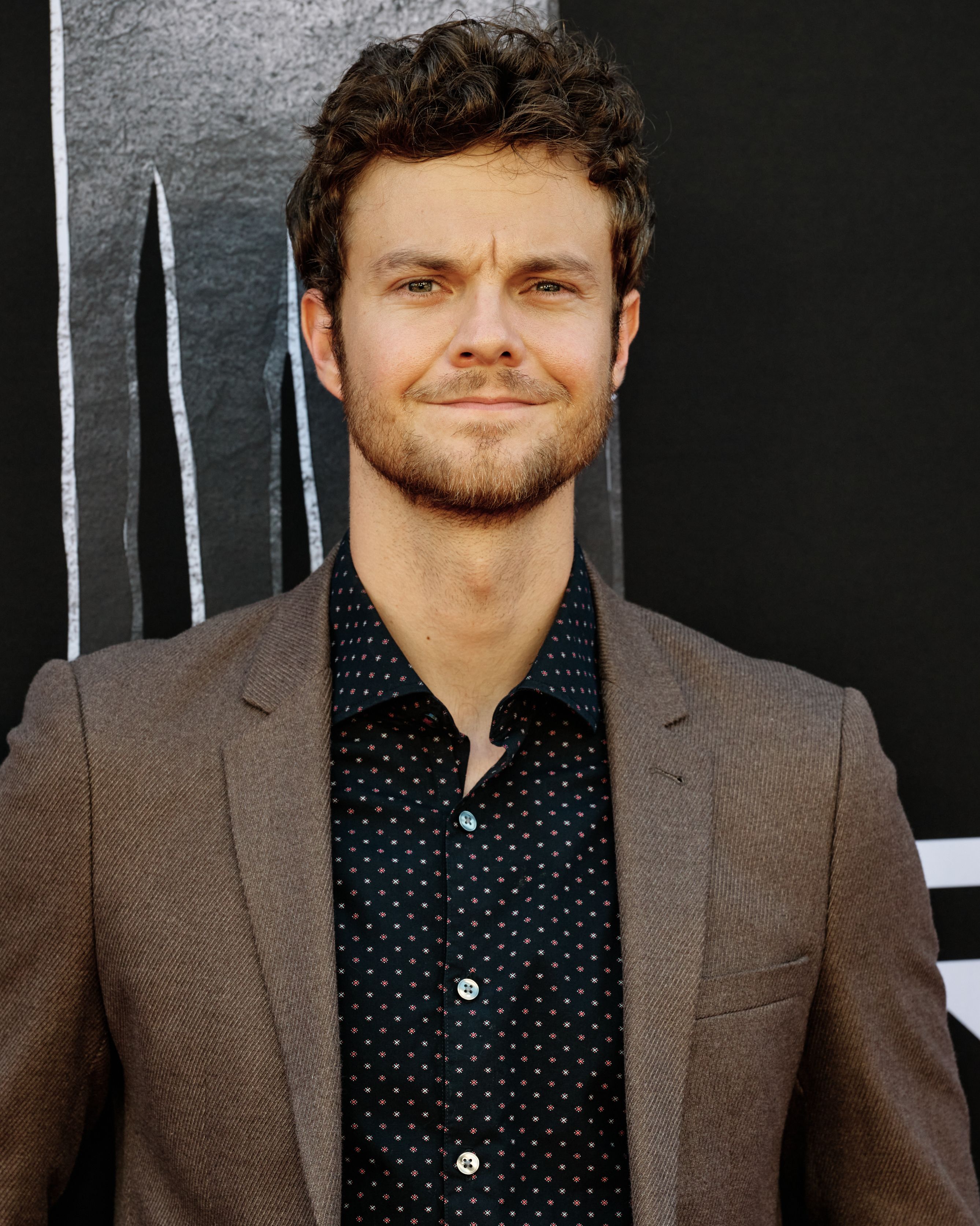 Jack Quaid wearing a brown blazer at the Prey film premiere