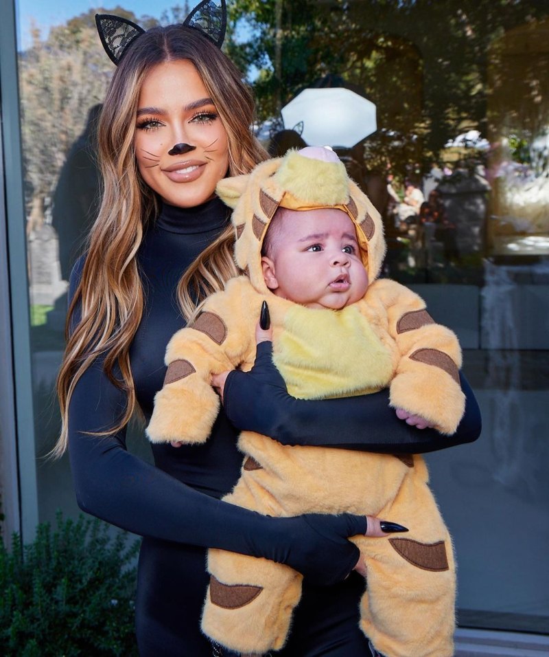 Khloe Kardashian dressed as a black cat holding Tatum dressed as a lion