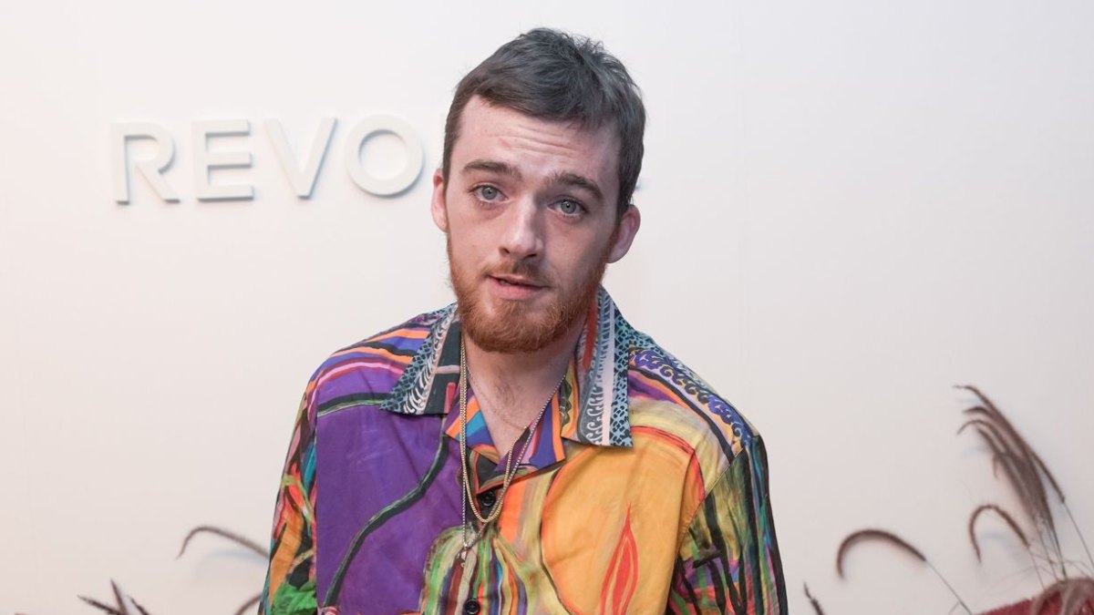 Angus Cloud wearing a multi-colored colalred T-shirt at a Revolve event