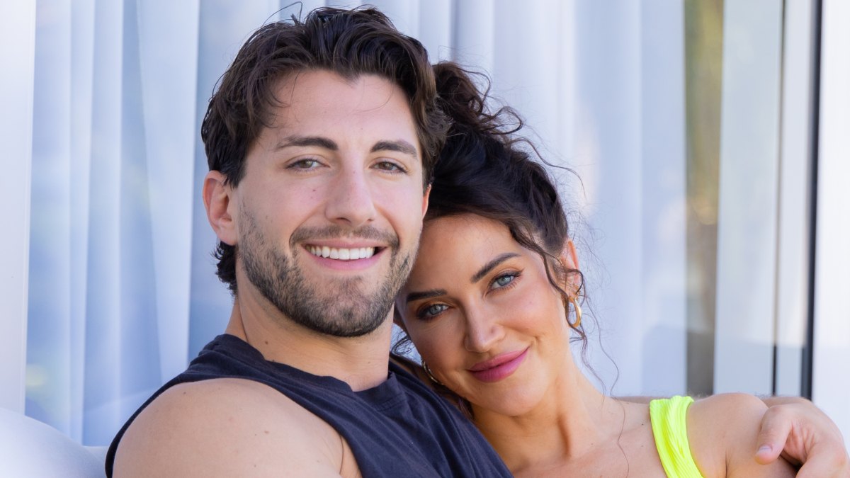 Jason Tartick wraps his arm around Kaitlyn Bristowe while smiling for a photo