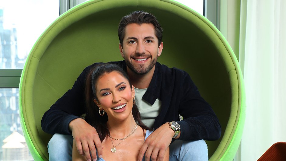 Kaitlyn Bristowe sitting on the ground in a blue dress with Jason Tartick behind her in a green chair