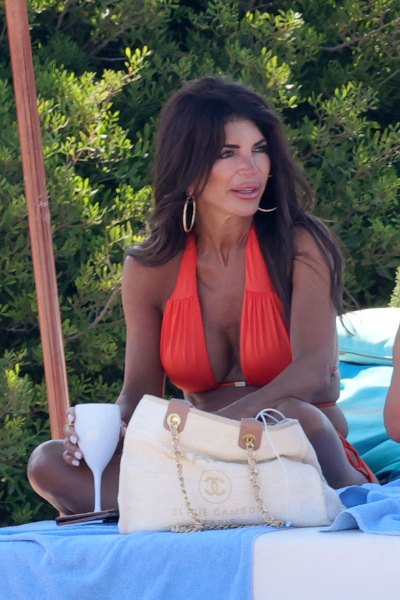 Teresa Giudice sitting on a beach bed in an orange halter bikini