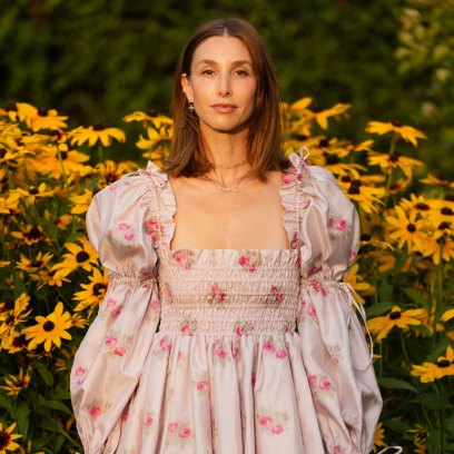 Whitney Port posing in a pink mini dress in a field of sunflowers