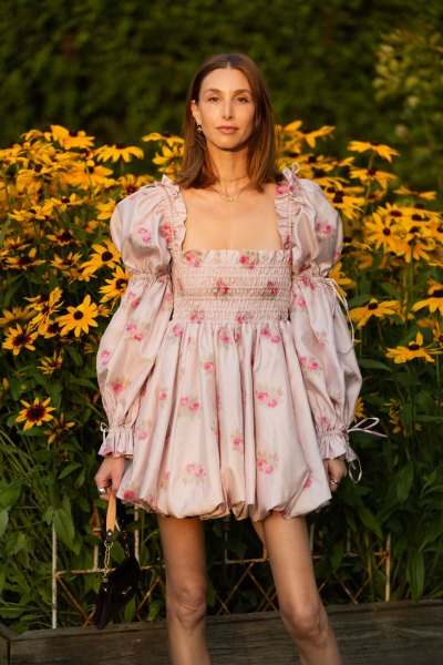Whitney Port posing in a pink mini dress in a field of sunflowers