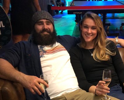 Jason Kelce wearing a white tshirt and black jacket next to wife, Kylie Kelce, wearing a black top.