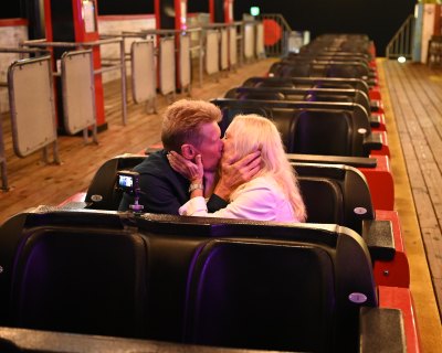 Gerry Turner and Ellen Goltzer kiss on an amusement park ride.