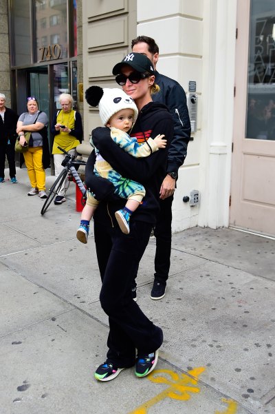 Paris Hilton wearing a black sweatsuit and black ballcap holding baby Phoenix.