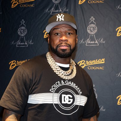 50 Cent promotes Branson cognac while wearing a black Dolce & Gabbana shirt and black New York Yankees hat