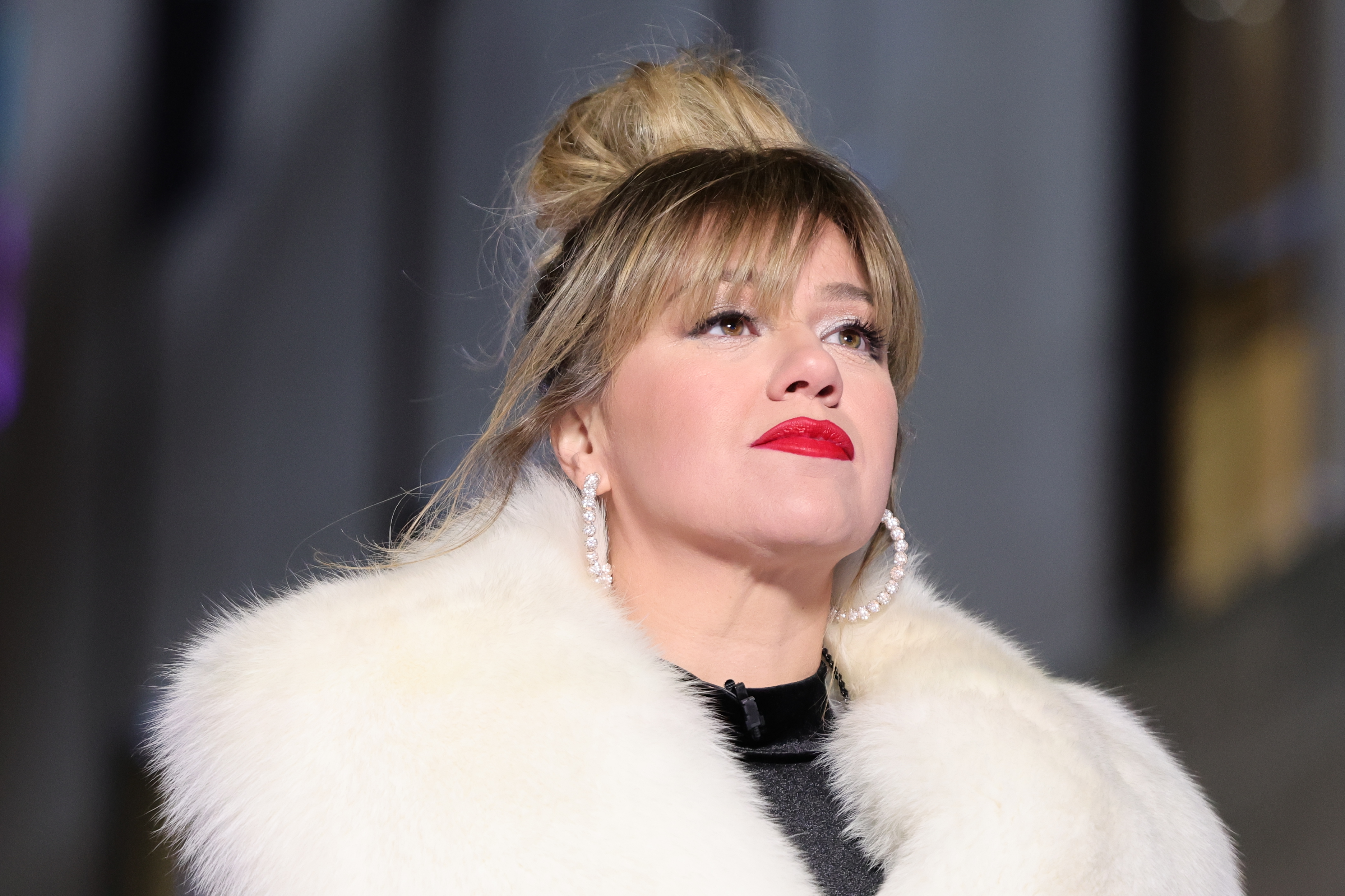 Kelly Clarkson wears her hair in an updo with a fur coat and black top underneath