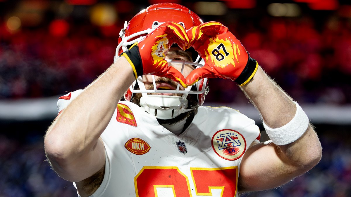 Travis Kelce giving Taylor Swift's signature heart hands gesture during Bills game.