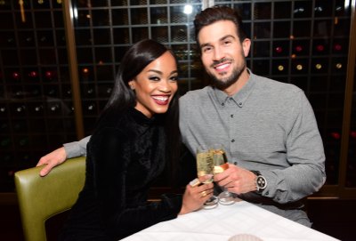 Rachel Lindsay wears all black while sitting next to Bryan Abasolo who's wearing a gray button down.