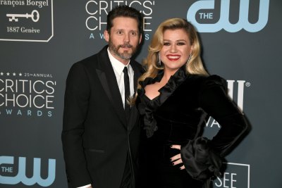Kelly Clarkson wears a black dress with fur cuffs next to Brandon Blackstock