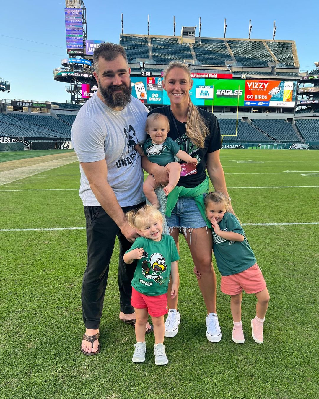 Kylie Kelce and Jason Kelce on the field with their three daughters.