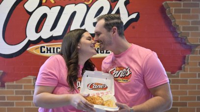 Love Is Blind's Alexa and Brennon Lemieux kiss while holding a box of Raising Cane's chicken tenders