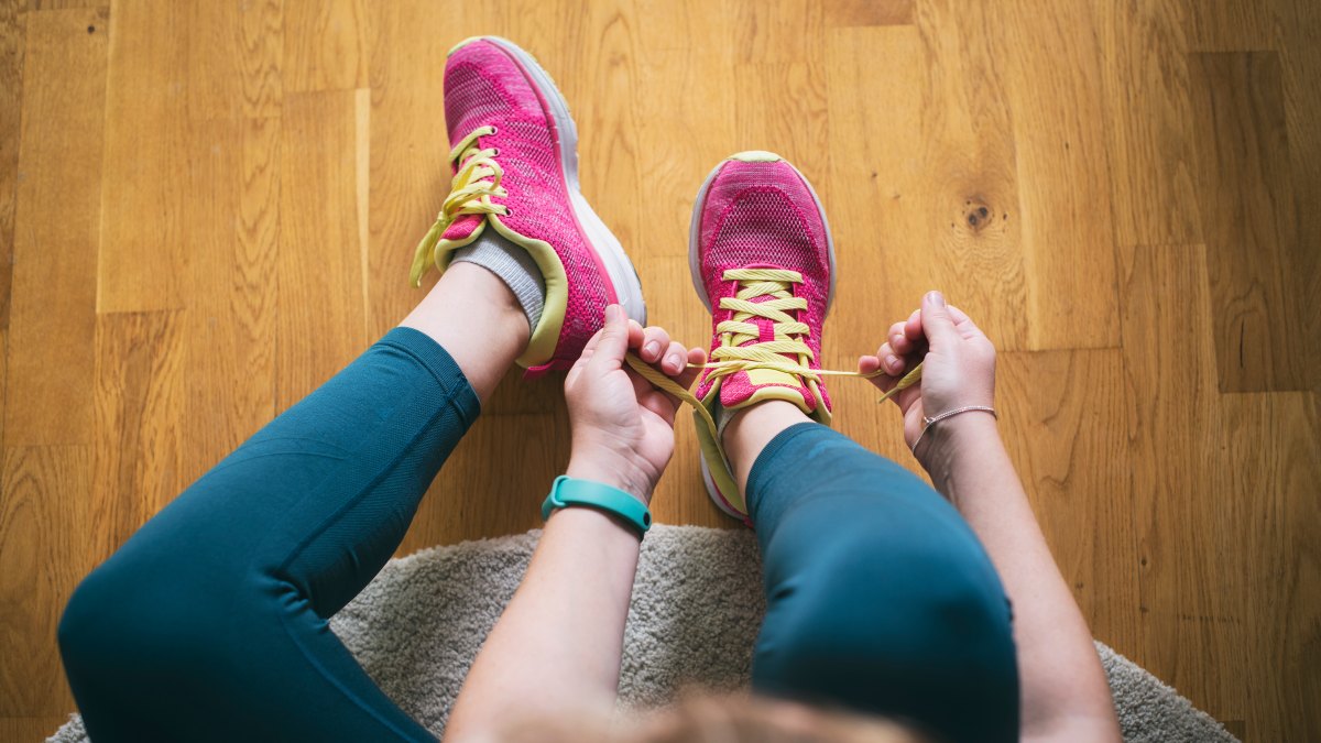 1402269119 Young sporty woman with smart watch tying shoelaces