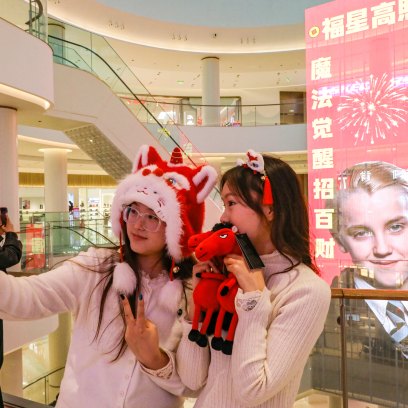 2259434667 Two women take photos in front of a giant Lunar New Year poster featuring English actor Tom Felton posing as Draco Malfoy, a character from the Harry Potter movies series, at a shopping mall in Shangqiu, in China's central Henan province on February 5, 2026. The character has become popular in China in the buildup to the Year of the Horse because the transliteration of his surname contains the Chinese characters for "horse" and "good fortune", making him an auspicious omen for the year ahead. (Photo by AFP via Getty Images) / China OUT