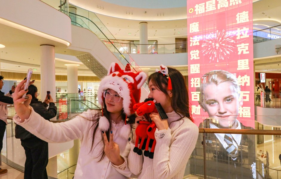 2259434667 Two women take photos in front of a giant Lunar New Year poster featuring English actor Tom Felton posing as Draco Malfoy, a character from the Harry Potter movies series, at a shopping mall in Shangqiu, in China's central Henan province on February 5, 2026. The character has become popular in China in the buildup to the Year of the Horse because the transliteration of his surname contains the Chinese characters for "horse" and "good fortune", making him an auspicious omen for the year ahead. (Photo by AFP via Getty Images) / China OUT